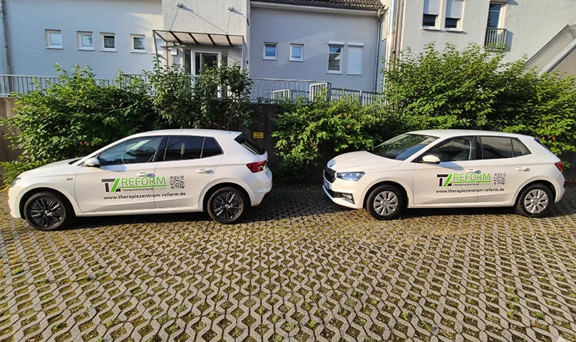 Dreistöckiges modernes Backsteingebäude mit geschwungener Fassade, großen Fenstern und Läden im Erdgeschoss an einer Straßenecke.